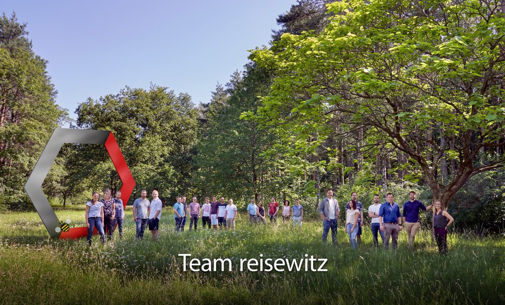 Eine Gruppe von Menschen steht auf einer Wiese im Wald mit den Worten Team reisewitz